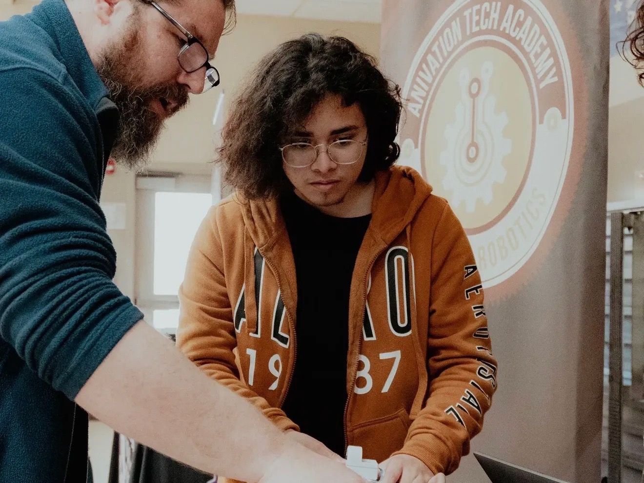 A teacher and a student working together at a robotics table at the Aviation Tech Academy.